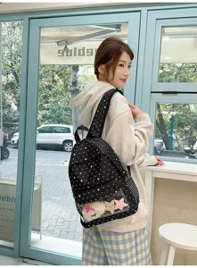 Détail de sac à dos à pois noir et blanc avec poche transparente et jouets en peluche.