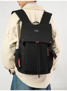 Close-up of black canvas backpack showing flap closure, multi pockets, and striking red zipper pulls.
