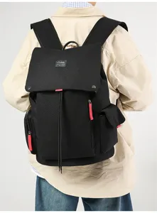 Detailed view of large capacity black canvas backpack with drawstring and red zipper pulls.
