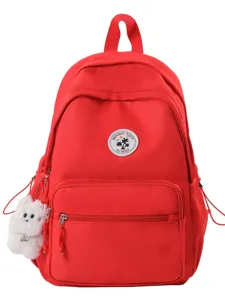 Zaino rosso brillante stile college per donna con simpatico portachiavi cucciolo e toppa con logo.