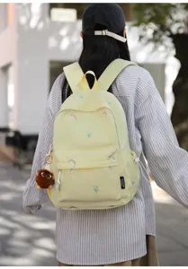 Casual cute embroidered backpack in light yellow with floral and rainbow details, detailed view.