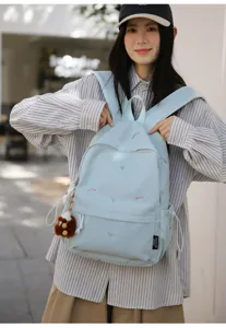 Detailed view of light blue Japanese style cute embroidered backpack with fuzzy bear pendant.