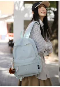 Detail view of the light blue embroidered backpack worn outdoors, showing cute flower and rainbow patterns.