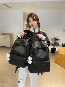 Casual black backpack for students, large capacity daily school bookbag with cute plush pendant.