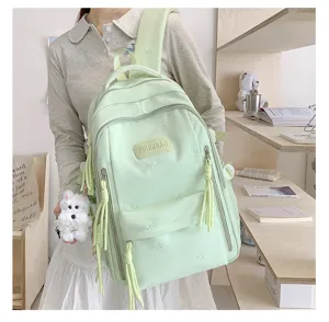 Sac à dos vert clair avec broderie de nœuds et pendentif en peluche pour un usage quotidien.