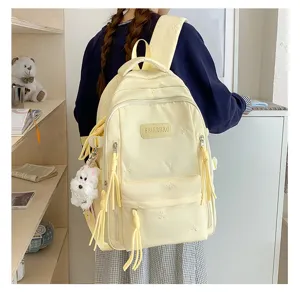 Vue détaillée du sac à dos en toile jaune clair avec jolie broderie de nœuds et un chien.