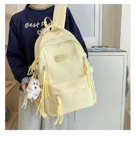 Vue détaillée du sac à dos jaune de style collège avec broderie nœud et charmant pendentif.