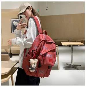 Detailed view of the red casual backpack featuring stylish letter prints and a cute bear pendant.
