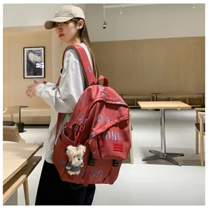 Red casual student backpack with bear pendant, trendy street style fashion travel bag detail view.