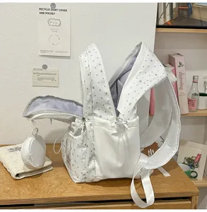 Dettaglio zaino scolastico bianco con motivo a stelle, scomparto aperto e tasca rotonda.