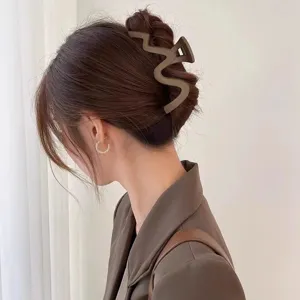 Detail shot of a large matte brown wavy hair claw clip worn elegantly on an updo hairstyle.