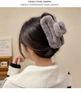 Detailed view of the oversized gray fluffy hair claw clip worn by a model, soft texture.