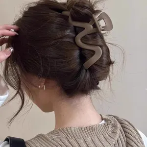 Detail shot of large matte brown wavy hair claw clip worn on hair back, elegant daily accessory.