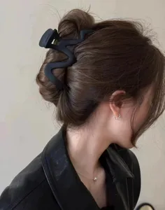 Detail view of large matte black wavy hair claw clip, elegant shark clip accessory for chic updo.