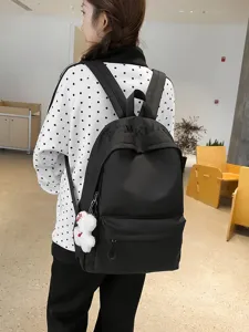 Detail view of the black canvas backpack featuring gothic embroidery and a cute bear pendant.