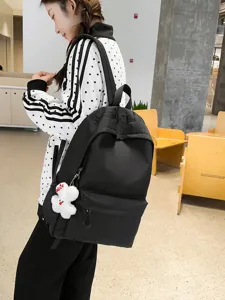 Classic black canvas backpack for women, large capacity casual daypack with cute plush pendant.
