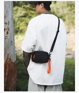 Detailed view of the casual crossbody bag worn outdoors, highlighting its orange accents.