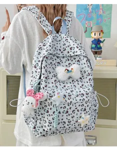 Detailed view of the cute blue leopard print backpack with plush bow and bunny charm.