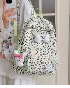 Light green leopard print backpack detail featuring cute plush toy charms and front pockets.