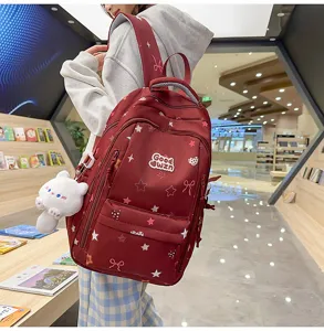 Detail view of a cute college-style red backpack with star prints and a lovely cat plush pendant.