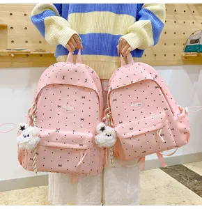 Pink polka dot school backpack detail view, cute bow pattern and lovely plush bear pendant.