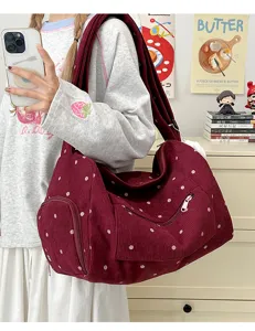 Detail shot of a retro red corduroy shoulder bag with white polka dots, casual daily wear.