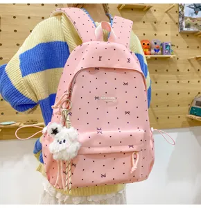 Detail view of the pink polka dot backpack with bow print, featuring a cute plush pendant.