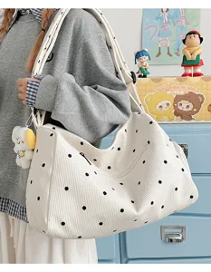 Detail view of a white corduroy polka dot hobo shoulder bag with a cute puppy plush pendant.