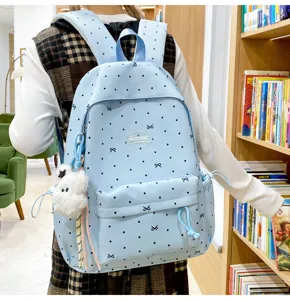 Light blue school backpack detail featuring cute bow patterns and fluffy plush pendant.