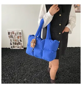 Detail view of royal blue puffer tote bag, soft quilted pillow bag with cute bear pendant.