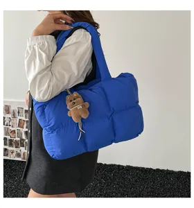 Blue quilted puffer tote bag with cute bear charm, soft padded shoulder bag for women.
