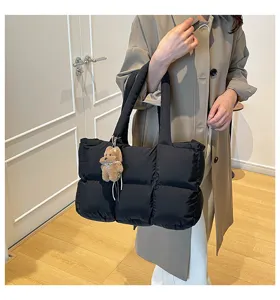 Detailed shot of black quilted puffer tote bag with cute bear charm and cozy soft texture.
