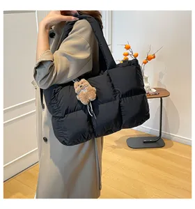 Detailed view of black quilted puffer tote bag with soft padded design and cute plush bear pendant.