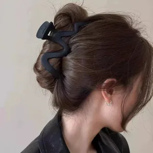 Large matte black wavy hair claw clip for women, elegant geometric shark hair accessory.