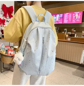 Detailed view of the light blue star print backpack with cute plush charm and zipper pocket.