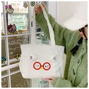 Close up detail of white corduroy lunch tote bag with cute cat ears and red glasses design.