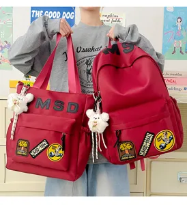 Detailed view of red canvas student backpack and tote bag set with cute bear charms and letters.