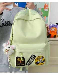 Detail view of light green casual student backpack with custom patches and cute plush pendant.