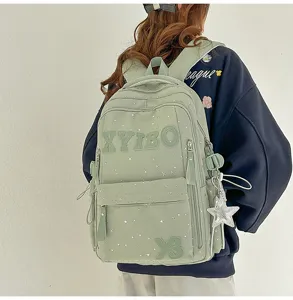 Detail view of the mint green star-patterned casual backpack with letters and pendant.