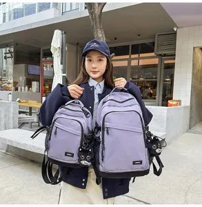 Detail view of purple minimalist backpack and small chest bag with cute cat charm for daily commute.