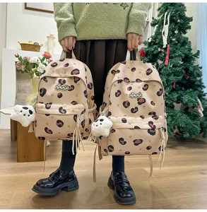 Detailed view of cute Korean style polka dot canvas backpack with plush charm and logo.
