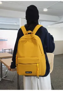 Vue détaillée d'un sac à dos d'étudiant jaune vif avec poche zippée et étiquette.