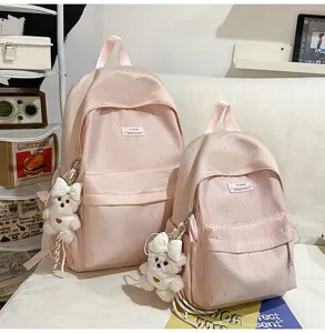 Close-up detail view of sweet pink polka dot school backpacks featuring cute bear pendants.