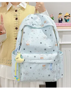 Close-up detail of cute dog print school backpack with plush moon pendant, canvas material.