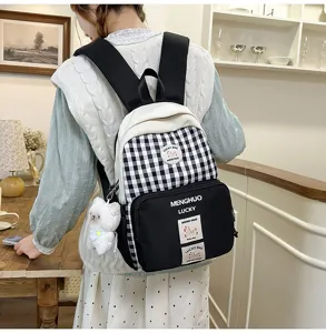 Detailed view of casual plaid backpack with front pocket, cute plush pendant, and shoulder straps.