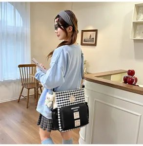 Canvas crossbody bag detail featuring black and white plaid pattern and cute plush bear charm.