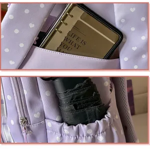 Vue détaillée de la poche avant et du rangement latéral du sac à dos violet à pois blancs.