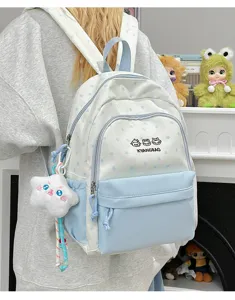 Detalle de mochila con estampado de estrellas, tejido bicolor, bolsillo frontal y lindos dijes.