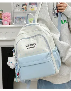 Vista detallada de mochila escolar azul y blanca con estrellas y bonito colgante de peluche.