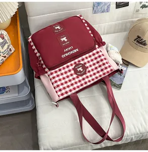 Detail view of the red and white plaid student canvas shoulder bag with cute bear patch.